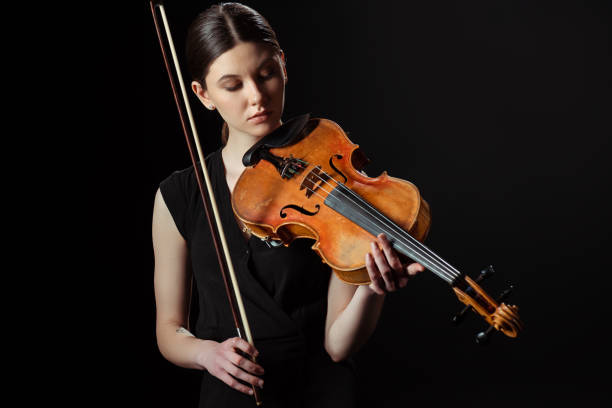 istock beautiful musician playing symphony on violin isolated on black 1249020959