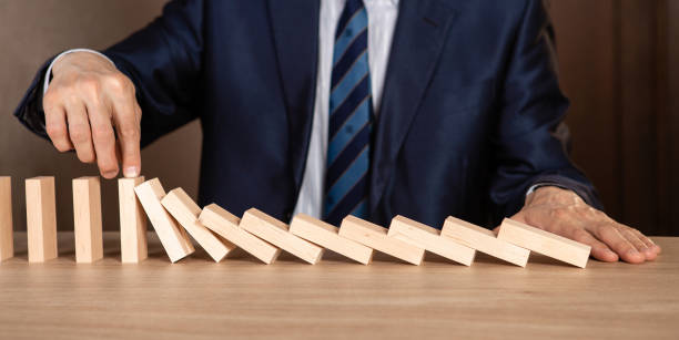 istock Businessman hand Stopping Falling wooden Dominoes effect from continuous toppled or risk, strategy and successful intervention concept for business. 1249021027