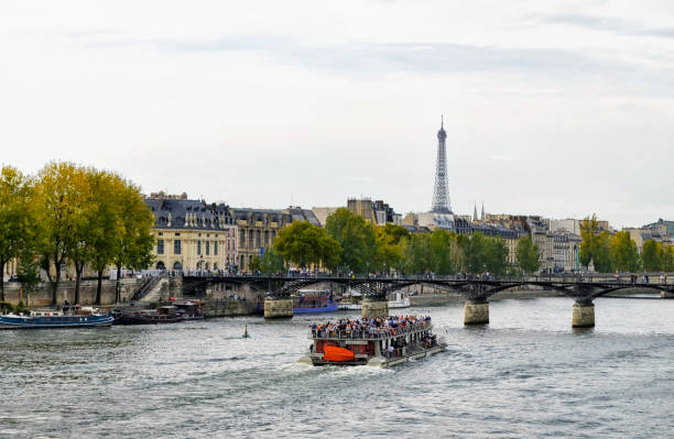 Paris, France - October, 2019: Looking from the Pont Neuf bridge towards the Left Bank - Rive Gauche. Seeing Paris from a boat on the Seine gives one a different perspective as well as a relaxing ride. Several companies operate tours on the Seine. In the distance is the pedestrian-only Pont des Arts bridge and the Eiffel Tower.