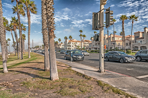 Huntington Beach, California, USA - October 11, 2017: In Huntington Beach this main roadway offers parking spaces with meters where the visitors can have access to the beach and ocean, with the many palm trees along this roadway and many residential style structures on the opposite side of the roadway with a cross walk available, this picture in October is very colorful and the ability to accommodates the beach loving visitors as well as others in the area.