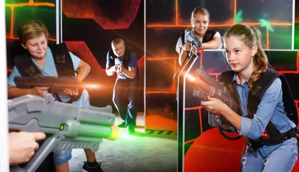 Photo of Happy teen brother and sister standing with laser pistols during