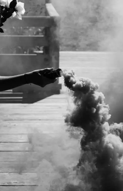 Black and White Photo of Person Holding Smokebomb and Flower