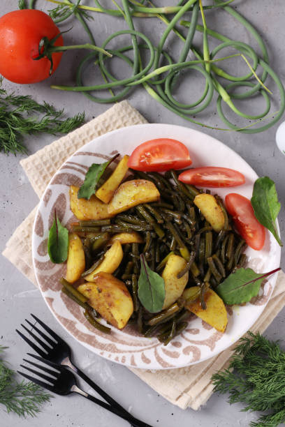 istock Potatoes cooked with garlic arrows in a plate on a gray concrete background, Top view 1249035535