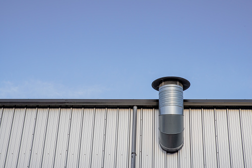 Chimney on the corrugated steel wall of an industrial warehouse.  Belfast, Northern Ireland.