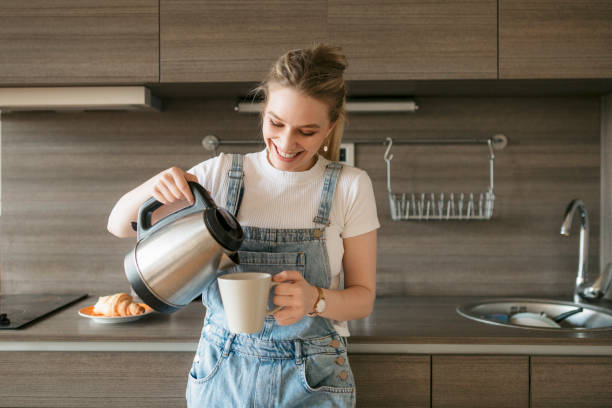 feliz joven que se sirve un poco de café por la mañana - hervidor fotografías e imágenes de stock