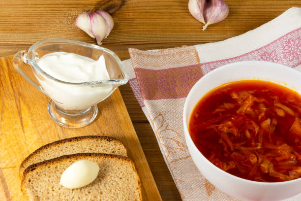 Lean borsch in a white bowl, sour cream, garlic and fresh rustic bread on a wooden table. Vegetarian food. Healthy lifestyle. stock photo