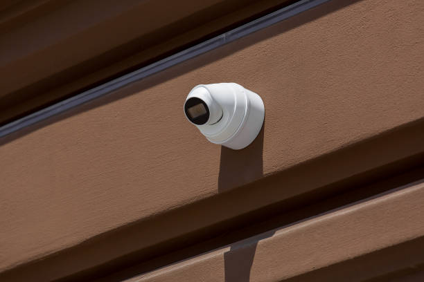 istock white CCTV camera installed on the exterior facade a brown building wall, close up video surveillance and crime tracking system. 1249044384