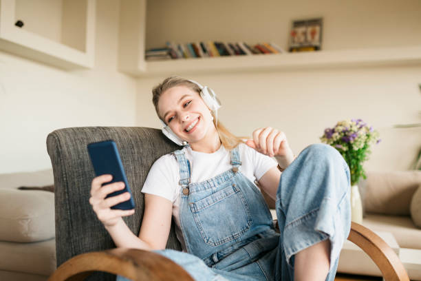 istock Smiling young woman relaxing at home, using a smart phone 1249048569