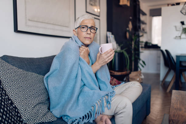 istock Ill senior woman sitting covered with blanket and drinking tea 1249050073