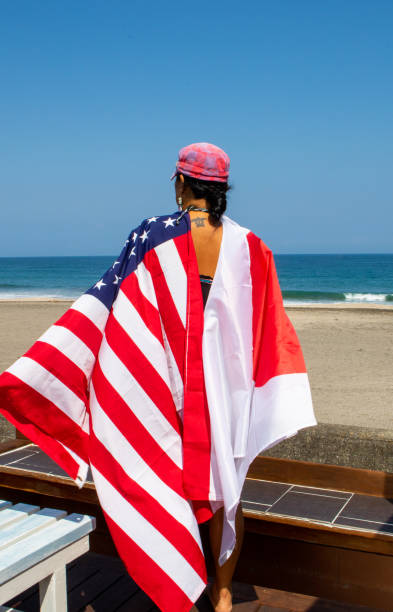 istock Asian lady wearing various county flags on her back while looking out to the ocean in Japan. 1249050193