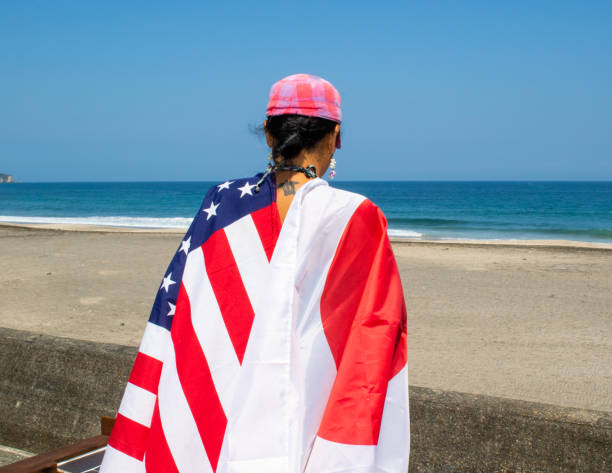 istock Asian lady wearing various county flags on her back while looking out to the ocean in Japan. 1249050208