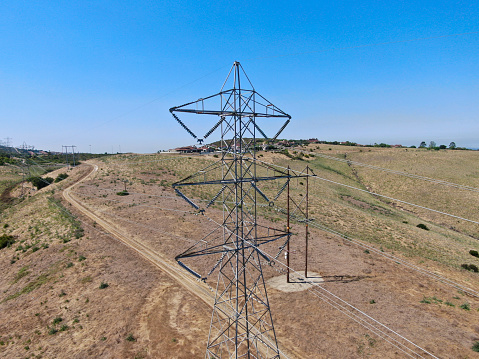 Aerial view of electricity transmission pylon in dry valley landscape. High voltage electricity distribution, California