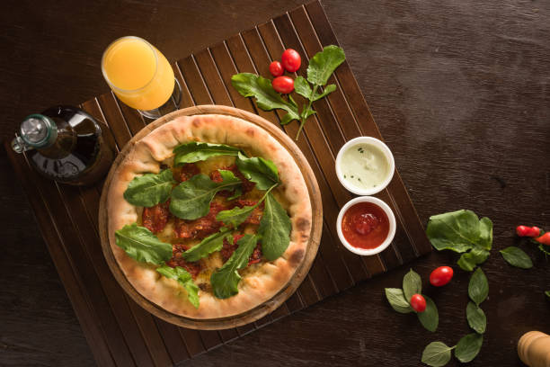 Dried tomato pizza with arugula, accompanied by orange juice.