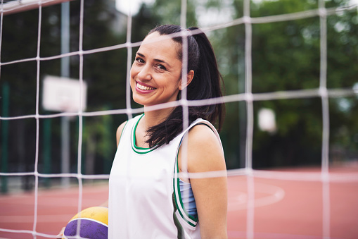 Smiling portrait of basketball woman on court.