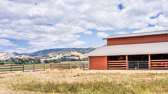 Landscape in a rural area of South San Francisco Bay, with wooden barn surrounded fields and mountains visible in the background; California