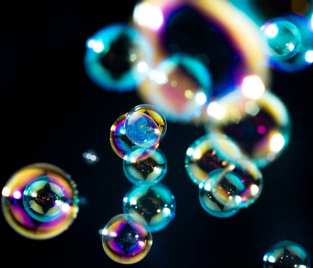 istock Colorful rainbow soap bubbles floating in the dark or black background. bubbles abstract background 1249081440