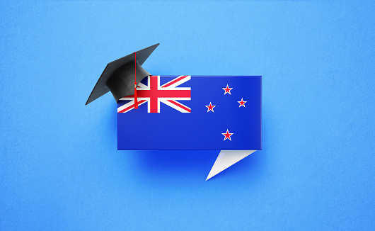 Graduation cap sitting over a speech bubble textured with New Zealand flag on blue background. Horizontal composition with copy space. Front view. Study in New Zealand concept.