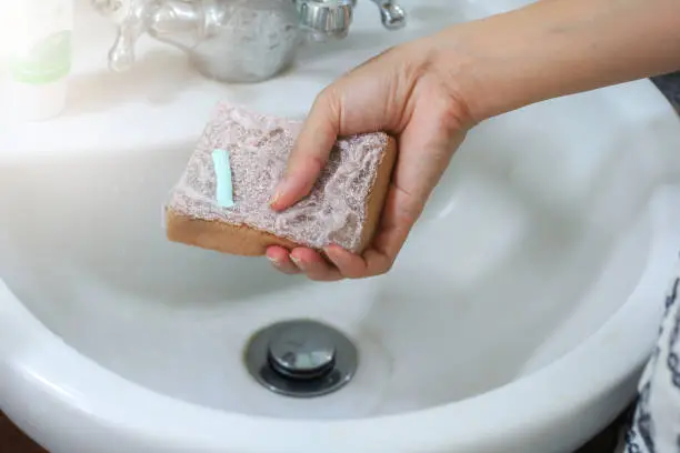 Using toothpaste to clean the washbasin in bathroom