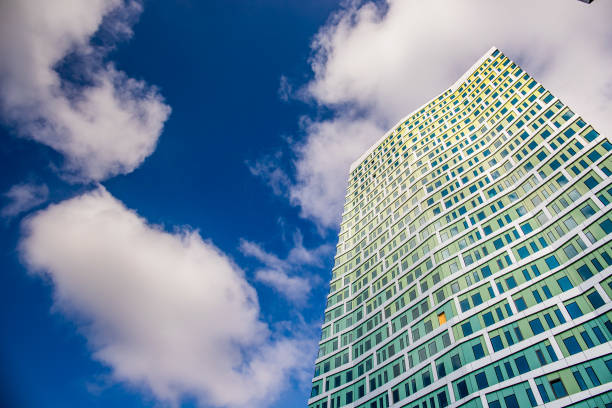 A tall green building rising against the blue skies on a summer day.