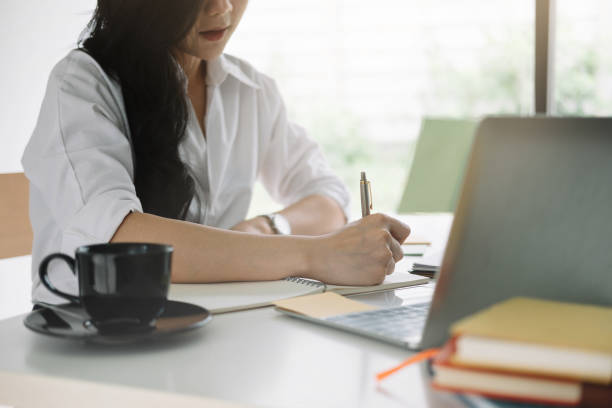 istock attractive woman writing in notepad while watching webinar on laptop 1249099664