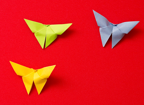 Red paper dove origami isolated on a blank grey background.