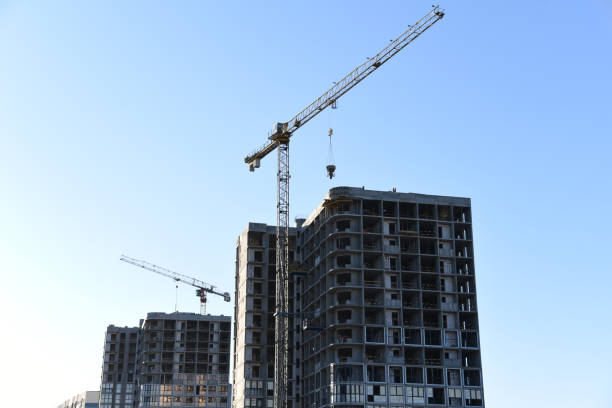 istock Tower crane lifting concrete bucket for pouring concrete during construction residential building on blue sky background 1249103810