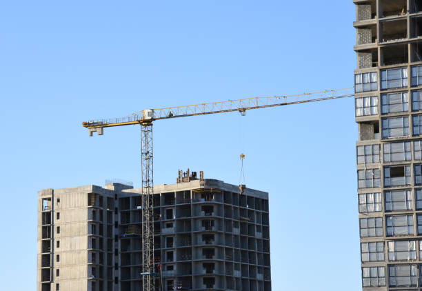 istock Tower crane lifting concrete bucket for pouring concrete during construction residential building on blue sky background 1249104007