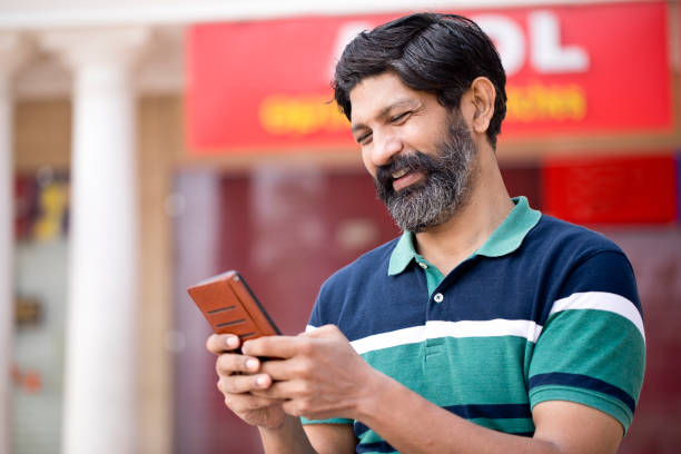 homme heureux textant sur le téléphone portable à l’extérieur dans la ville - technology typing male beauty asian and indian ethnicities photos et images de collection