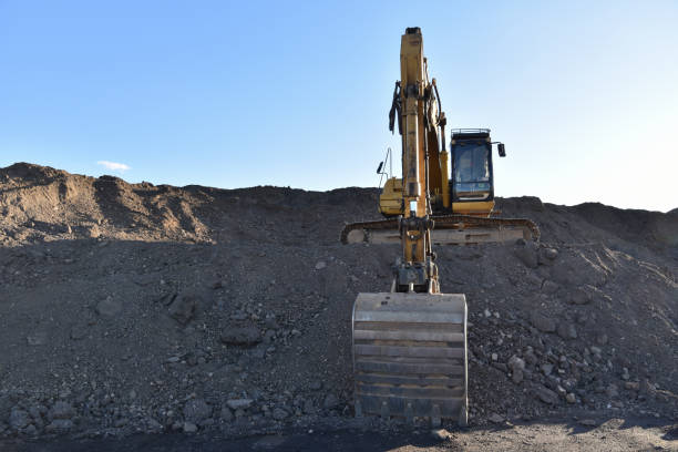 istock Excavator working at construction site. Backhoe digs ground in sand quarry on blue sky background. 1249111513