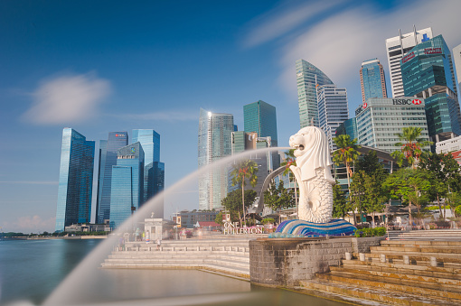 Singapore, Singapore - July 20, 2014: Tourist beside the Merlion statue fountain, iconic symbol of Singapore, overlooking the Marina Bay waterfront, the Esplanade Theatres, luxury hotels