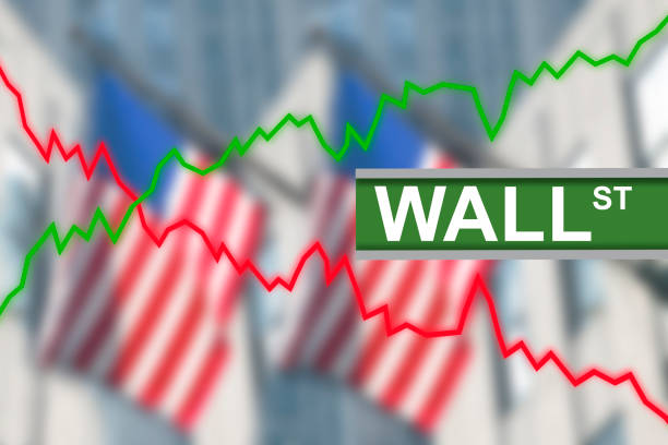 istock Wall Street sign post with green line indicating stock market going up and red down. Blurred background of American US flags hanging from buildings 1249114693
