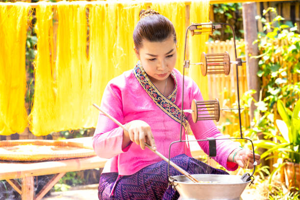istock Crafts and craftsmanship. Boiling silk threads and making silk threads. Yarn warping machine in a textile weaving crafsmanship. Hand of woman weaving and spinning natural colorful threads or yarn. 1249115521