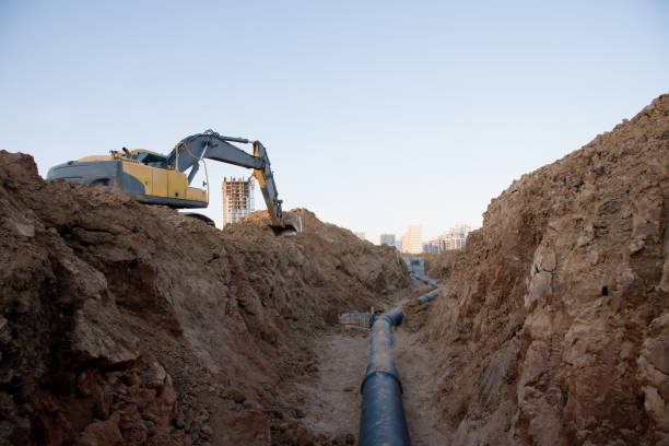 istock Excavator at work trenching at a construction site. Trench for laying external sewer pipes 1249115781