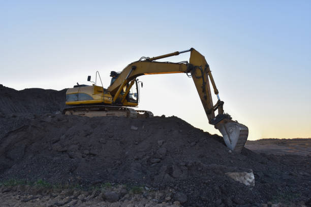 istock Yellow excavator during earthmoving at open pit on blue sky background 1249115940