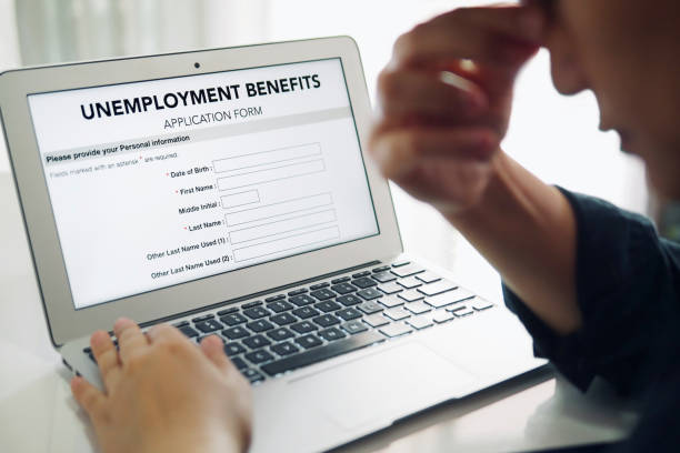 arbeitslose depressive person ausfüllen ein online-arbeitslosengeld-antragsformular mit laptop-computer. - unemployment rate stock-fotos und bilder