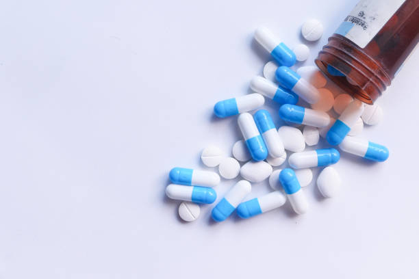 istock Close up of colorful capsules spilling from container on white background 1249121206