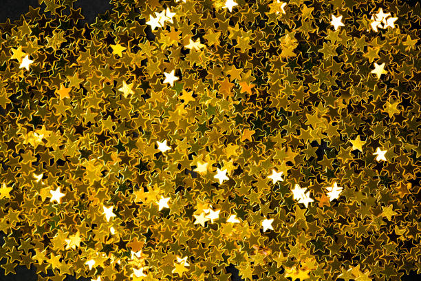 paillettes de poussière d’étoile d’or sur un fond noir de pile pour noël et nouvelle année heureuse, luxe de texture et décoration élégante - confetti gold black star shape photos et images de collection