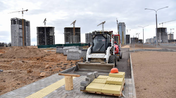 Skid-steer loader on Laying paving slabs at construction site. Process of installing paving bricks in the town pedestrian zone. Screeding the sand for install concrete blocks. Road works for pavement renovation