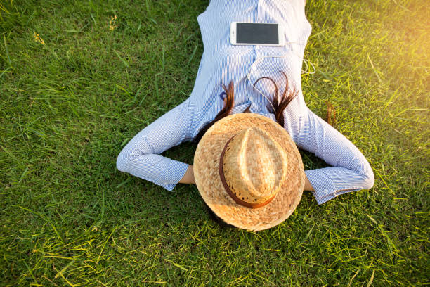 красивая женщина, лежащая и расслабляющая на зеленом поле - lying down women laptop freedom стоковые фото и изображения
