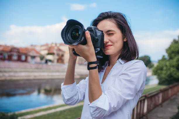 istock Happy woman smiling with a camera in the park 1249144613