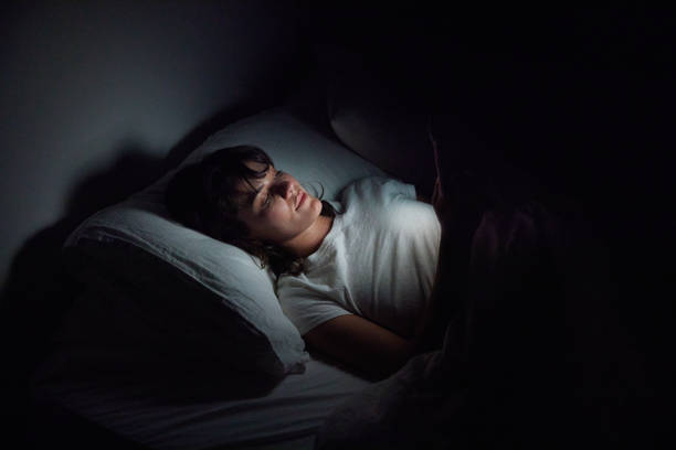 istock Young woman using her cellphone late at night in bed 1249145494