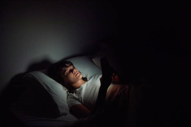 istock Young woman checking her cellphone in bed at night 1249145578