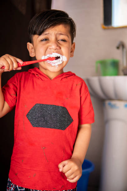 istock Cute little boy brushing teeth with red toothbrush. 1249146191