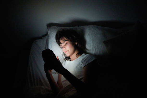 istock Young woman using her cellphone in bed at night 1249146892