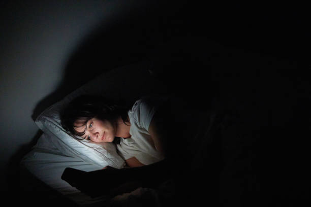 istock Young woman checking her phone while lying in bed at night 1249147014