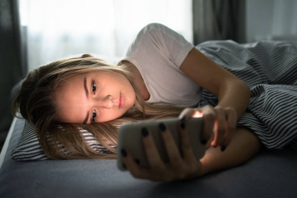 istock Pretty, young woman using her smart phone in bed 1249147185