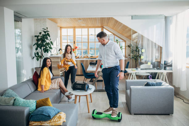 Man entertaining his family while riding hoverboard in living room Young man entertaining his family while riding hoverboard in living room at home. hoverboard stock pictures, royalty-free photos & images