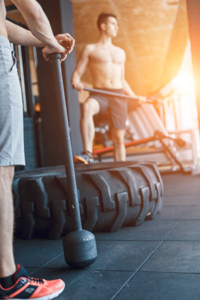 istock two Young man with a hammer strike on a tire in the gym. Workout. 1249156354
