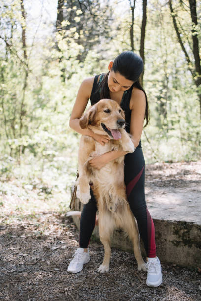 istock Lady in park cuddling her golden retriever 1249156444