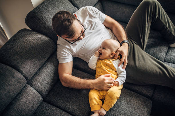 istock Father and baby son relaxing on sofa together 1249156480